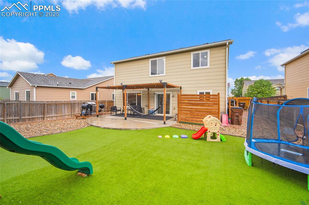 Image 30 of 50: Rear view of property featuring a playground, a trampoline, a fenced backya