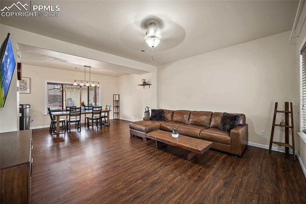 Image 4 of 50: Living room featuring dark wood-type flooring and ceiling fan
