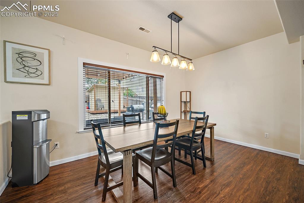 Image 7 of 50: Dining area with dark wood finished floors and baseboards