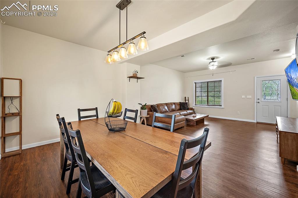 Image 8 of 50: Dining space with dark wood-style floors and baseboards