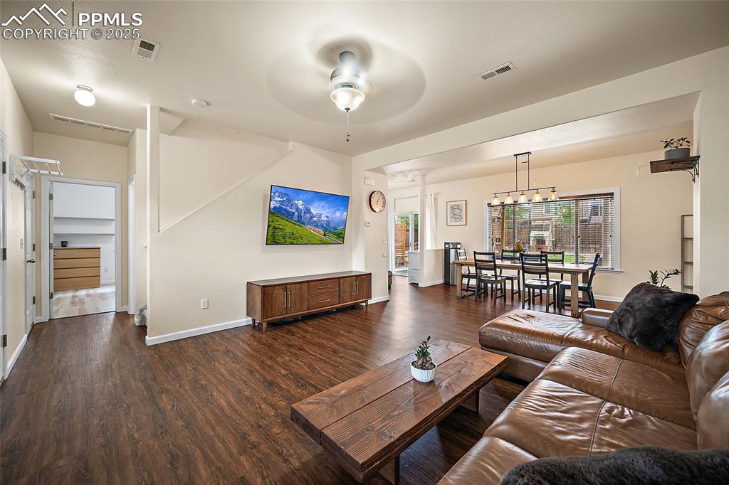 Image 9 of 50: Living room with ceiling fan and dark wood-style floors