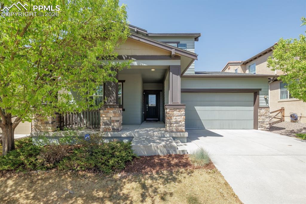 Image 3 of 50: Contemporary residence featuring a covered front porch with stone-clad colu