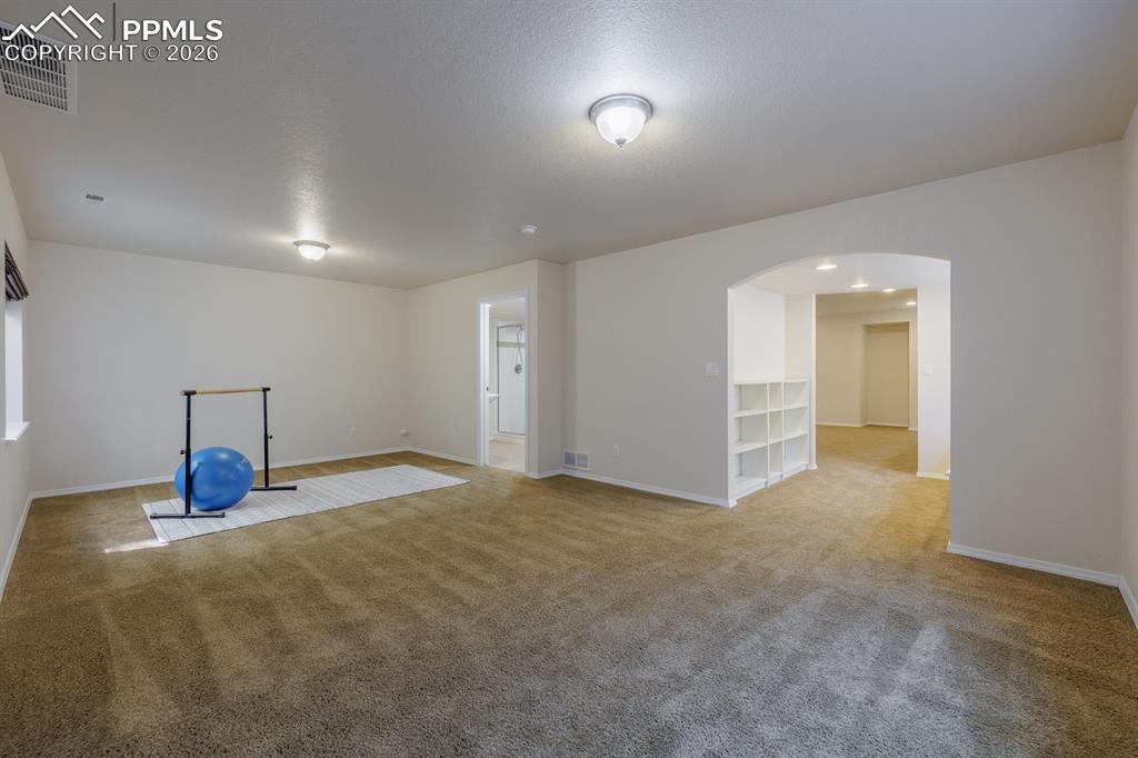 Image 42 of 50: Spacious lower-level room featuring built-in shelving, integrated window se