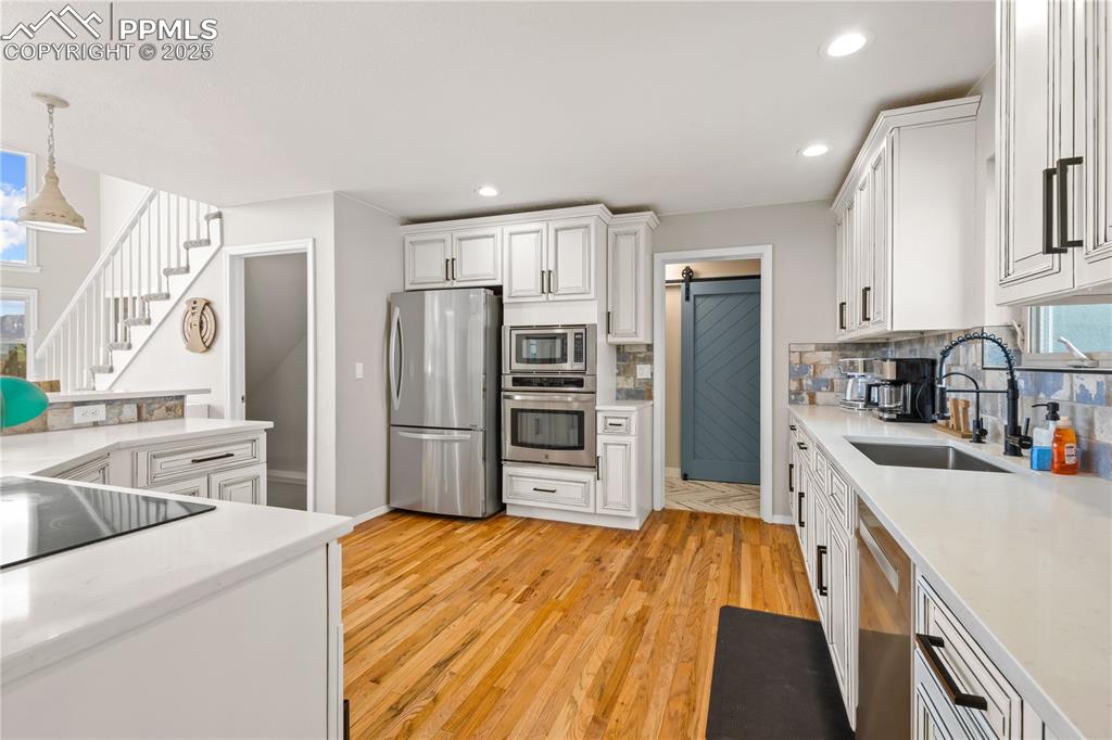 Image 11 of 48: Hardwood floors in the main level in the kitchen, newer stainless steels ap