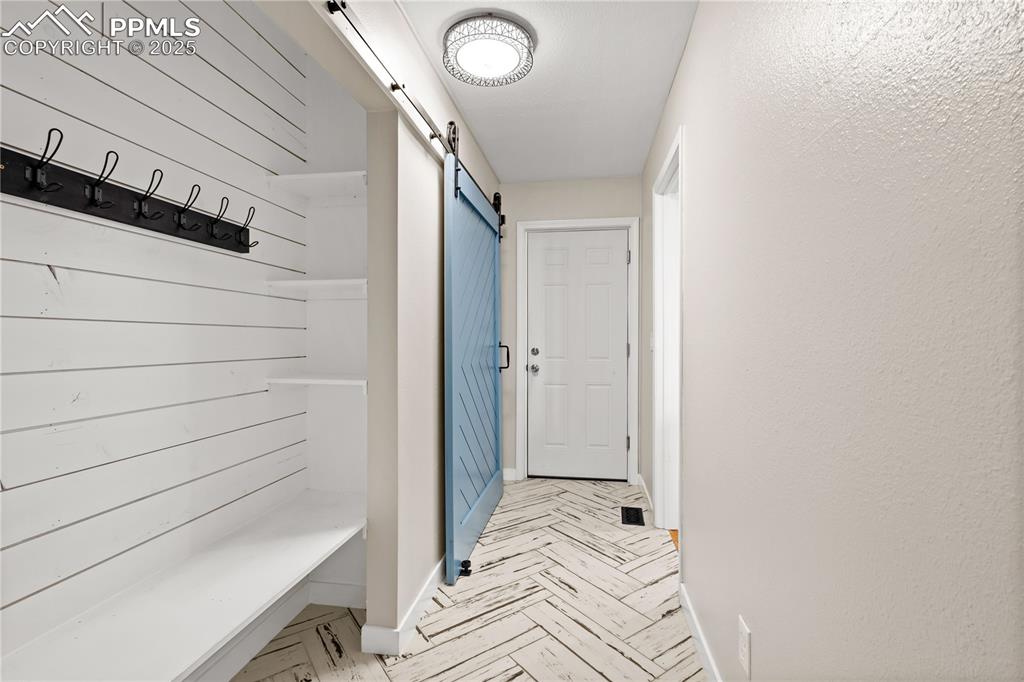 Image 15 of 48: Mudroom with a barn door to hide the spacious pantry, door to attached gara