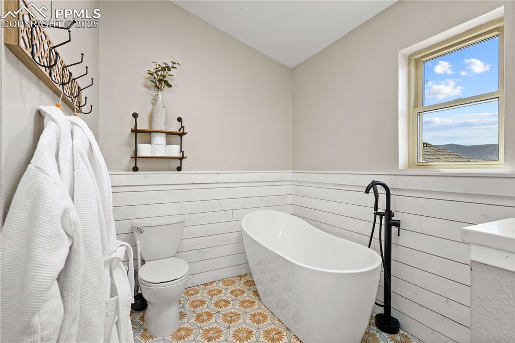 Image 19 of 48: Master bathroom featuring wainscot, a soaking tub and toilet.