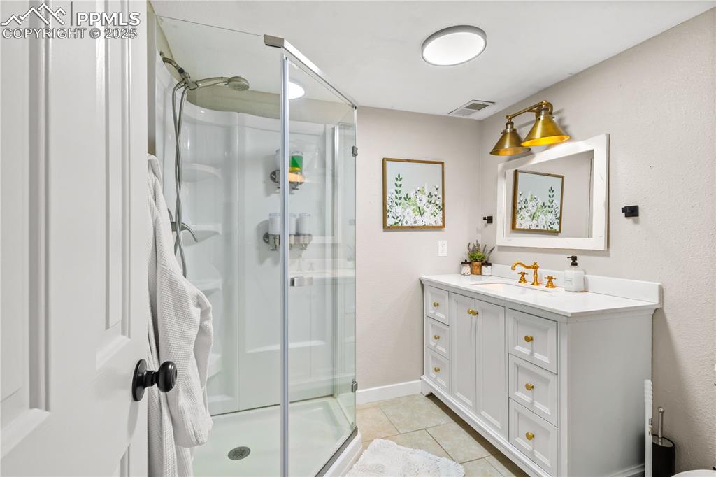 Image 34 of 48: Basement 3/4 bathroom is white and has lots of cabinet storage. 