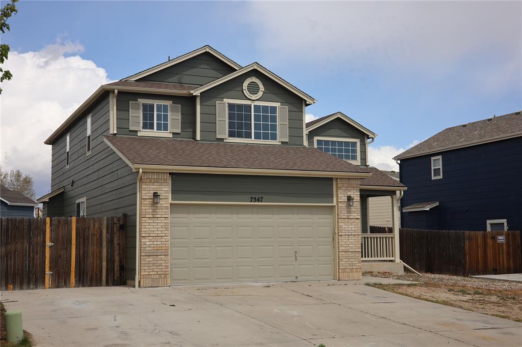 Caption: Two-story residence featuring a two-car garage with a light-colored door, brick accents, and a cover