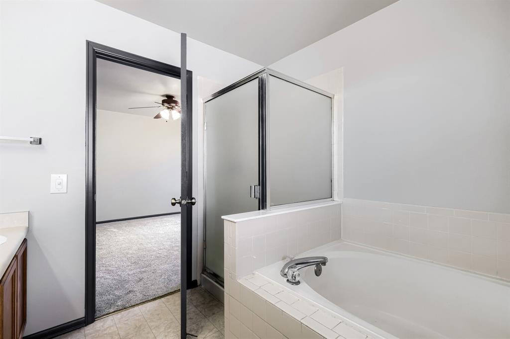 Image 12 of 27: Bathroom featuring a tiled tub surround, a shower with a frosted glass encl