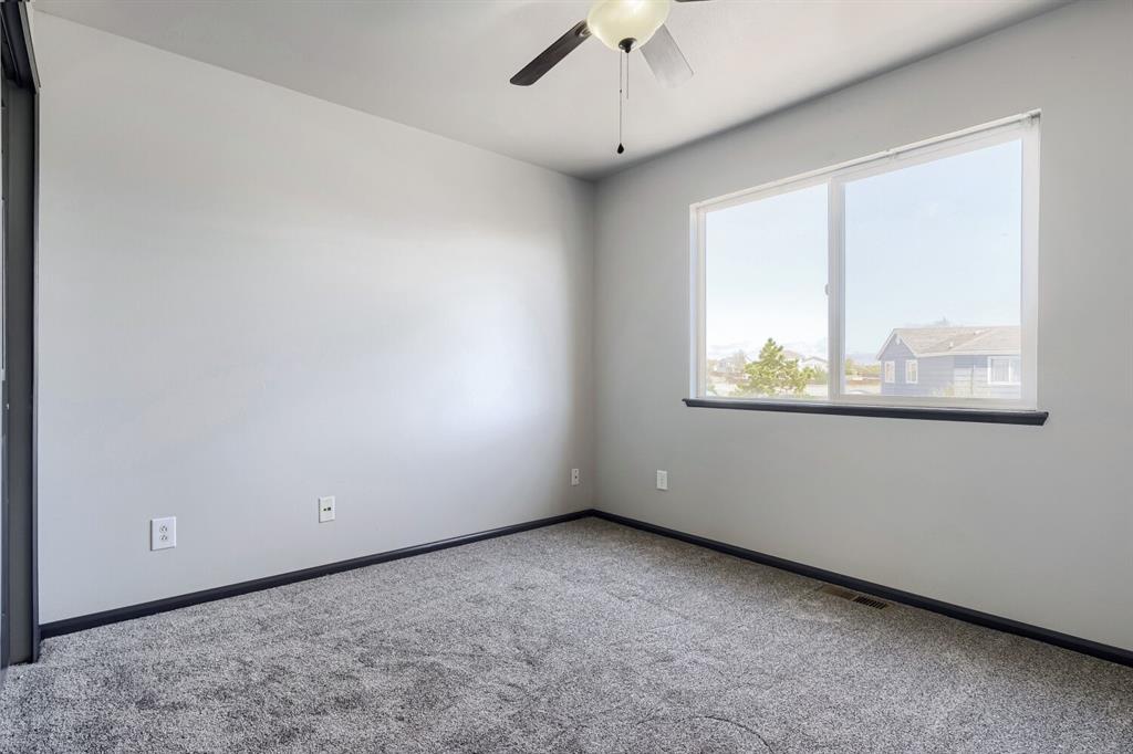 Image 15 of 27: Bedroom featuring light gray wall paint, dark gray baseboards, and neutral 