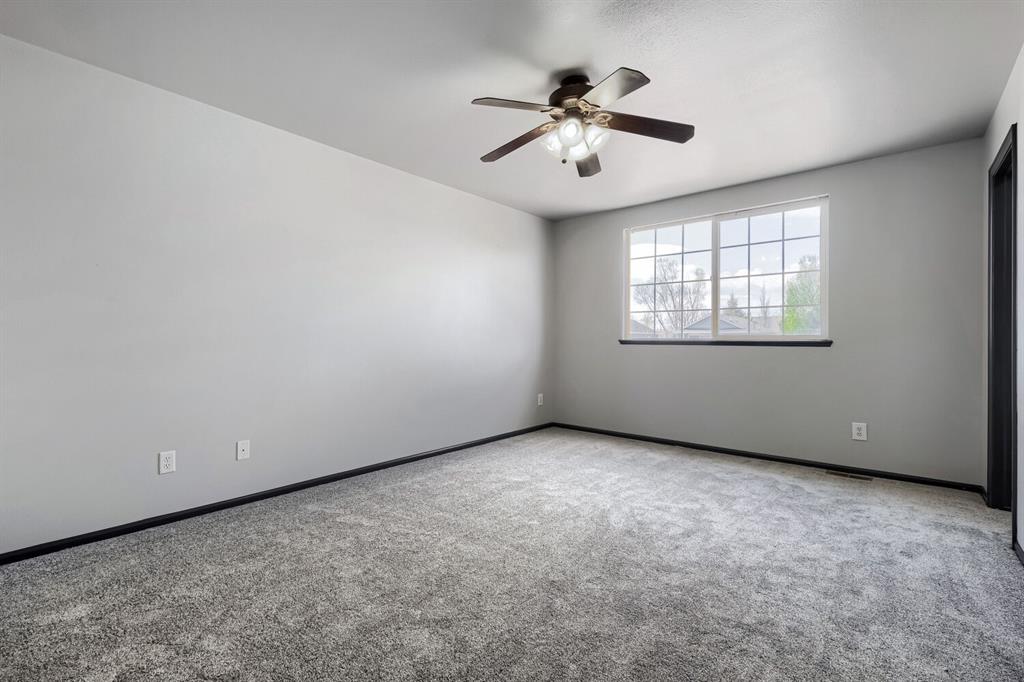Image 18 of 27: Spacious room featuring neutral grey walls and plush grey carpeting