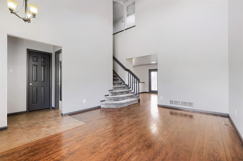 Image 2 of 27: Two-story entry featuring wood-finish flooring, a carpeted staircase with d
