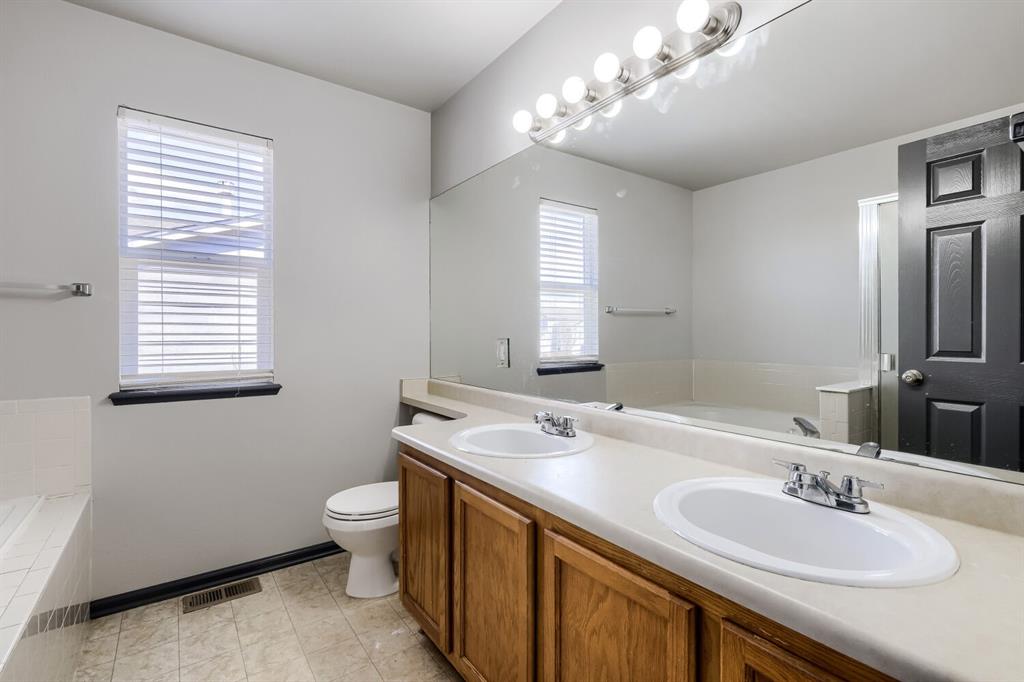Image 20 of 27: Bathroom featuring a double vanity with wood-finish cabinetry, a large inte