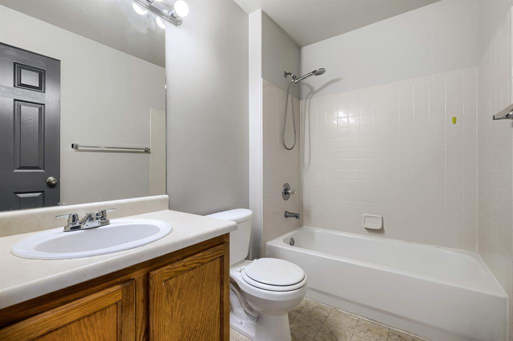 Image 21 of 27: Bathroom featuring a wood-finish vanity with a light-toned countertop and i