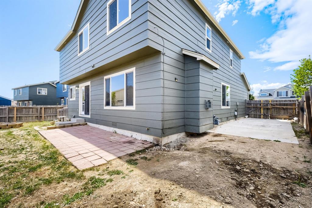Image 25 of 27: Rear exterior featuring horizontal siding, multiple windows, and a sliding 