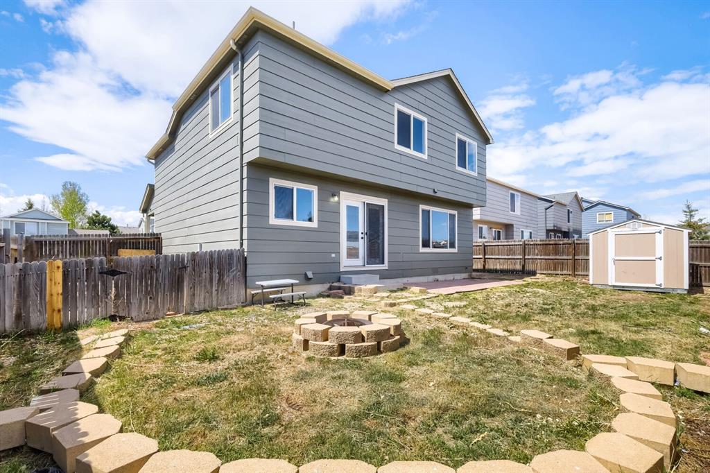 Image 26 of 27: Expansive backyard featuring a two-story residence with gray siding, multip