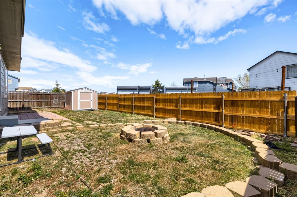 Image 27 of 27: Spacious backyard featuring a stone fire pit, a storage shed, a privacy fen