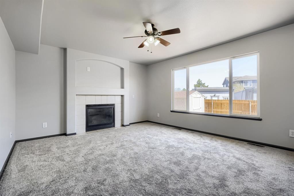 Image 3 of 27: Spacious living area featuring a fireplace with a tiled hearth and mantle, 