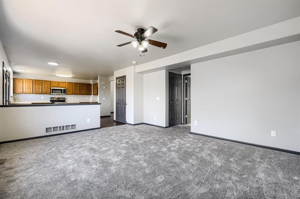 Image 4 of 27: Expansive carpeted area with a ceiling fan, offering an open-concept design