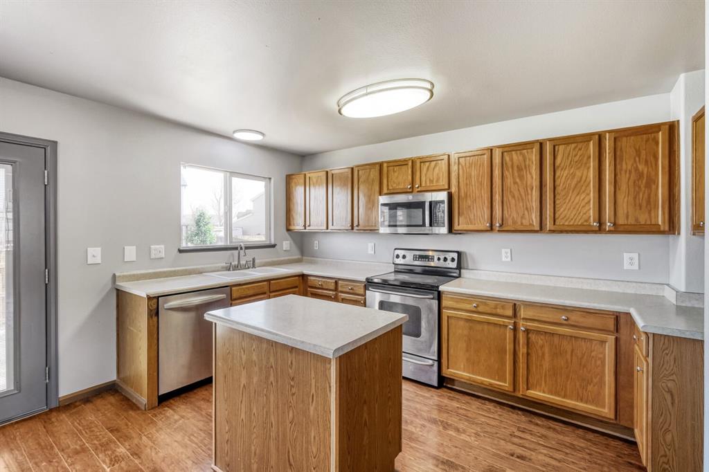 Image 7 of 27: Kitchen featuring wood-finish flooring, a central island with a light-toned