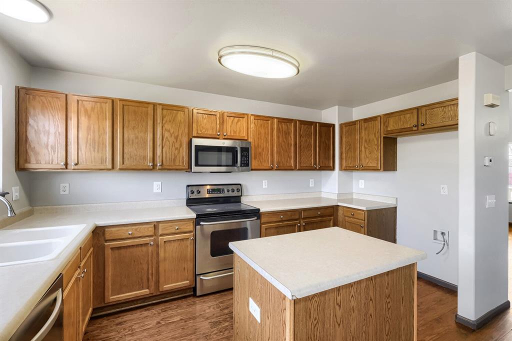 Image 8 of 27: Kitchen featuring wood-finish cabinetry, light-toned countertops, and a cen
