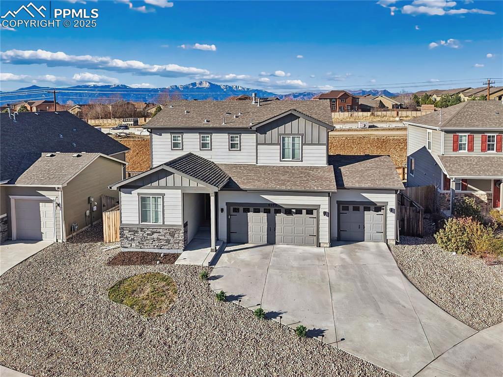 Caption: exterior with a true 3-car garage and low-maintenance landscaping, set against scenic mountain views