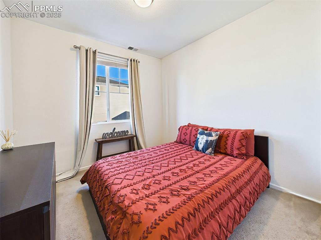 Image 22 of 50: Versatile main-floor bedroom with carpeted flooring and a large window—idea