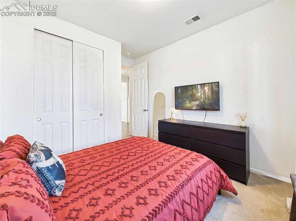 Image 23 of 50: Secondary main-level bedroom with ample closet space and clean, neutral fin