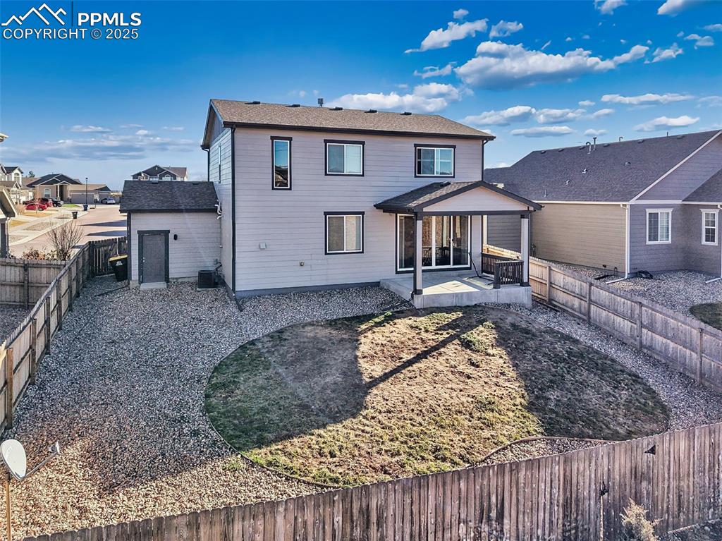 Image 45 of 50: Generous yard space extends around the home, with private fencing and a wid