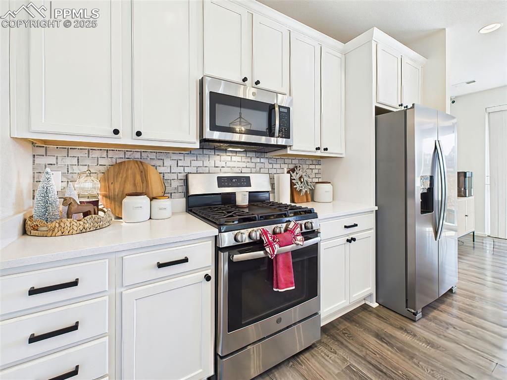 Image 7 of 50: Stainless steel gas range, vented microwave, and classic tile backsplash ad