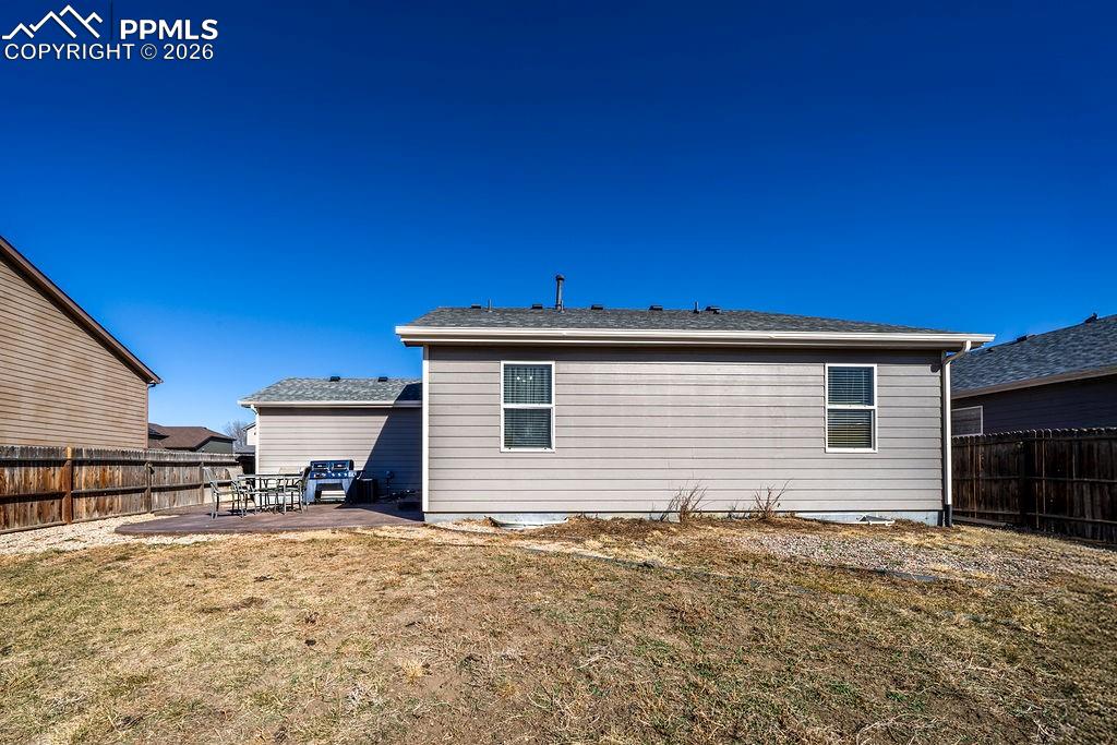Image 43 of 48: Rear view of home, patio and fenced backyard.
