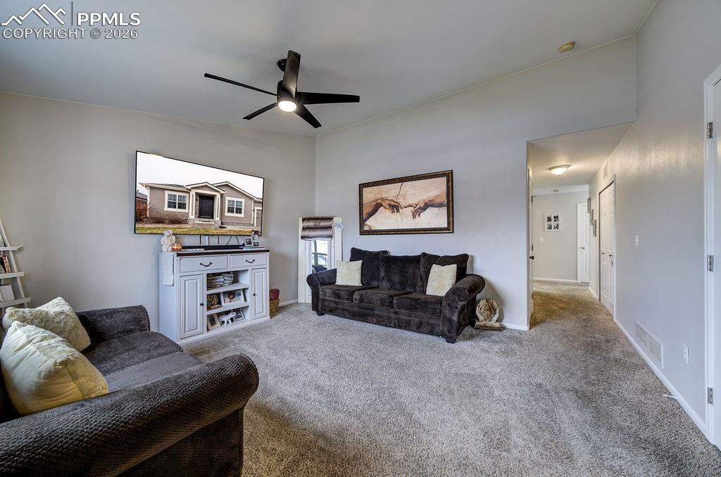 Image 5 of 48: Spacious Living Room with lighted ceiling fan and neutral carpet.
