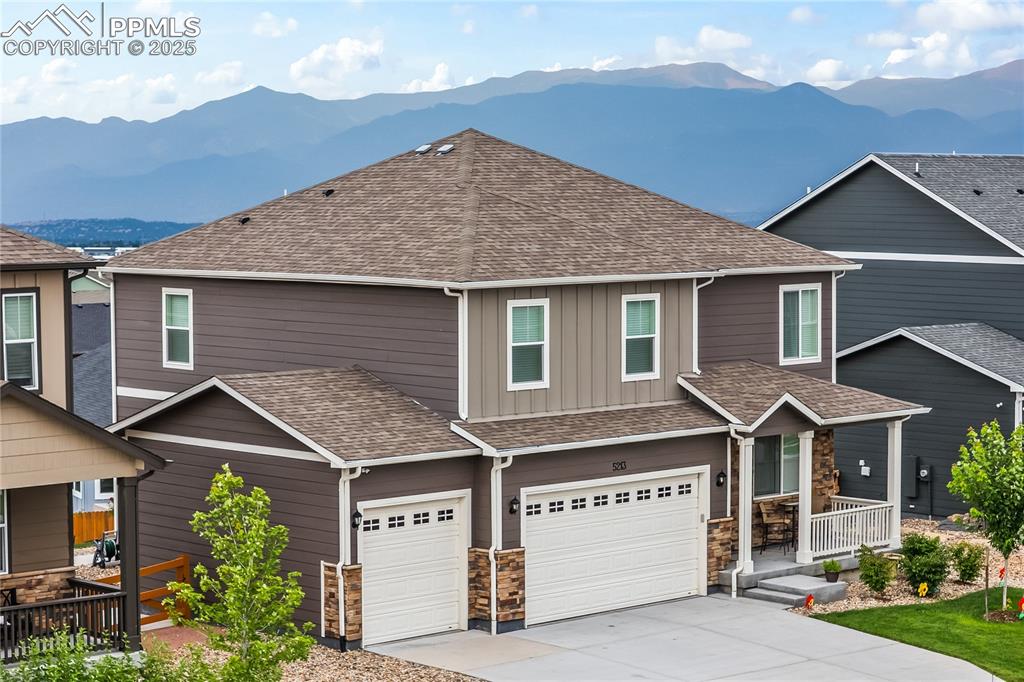 Caption: Craftsman-style house with a garage, a mountain view, roof with shingles, and board and batten sidin
