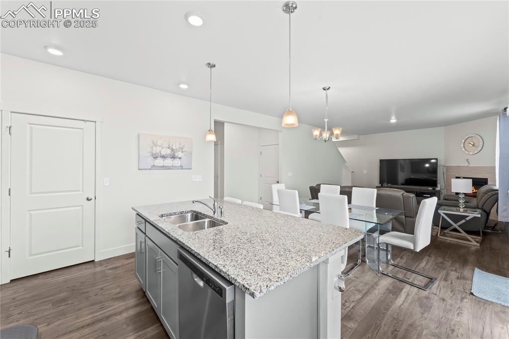 Image 13 of 39: Kitchen with light stone countertops, dishwasher, gray cabinetry, open floo