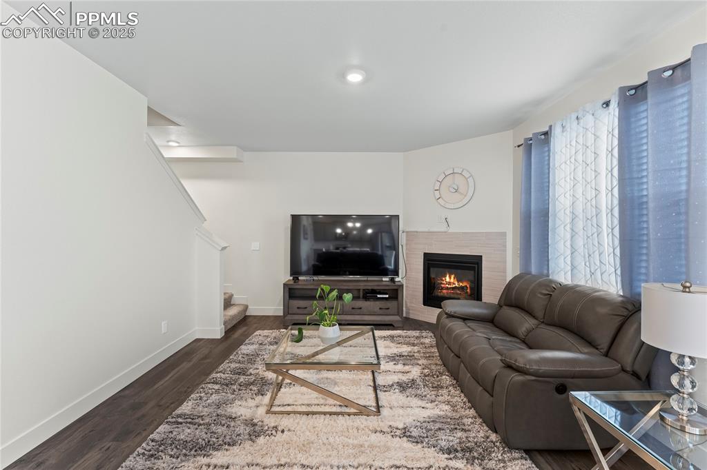 Image 15 of 39: Living room with a fireplace, stairway, and dark wood finished floors