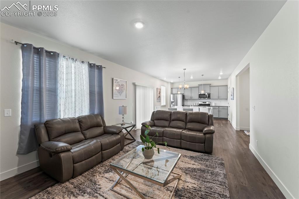 Image 16 of 39: Living area with a chandelier, dark wood-style floors, and recessed lightin
