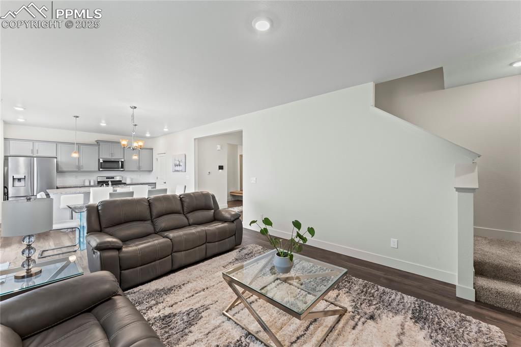 Image 17 of 39: Living room with a chandelier, stairway, dark wood-style flooring, and rece