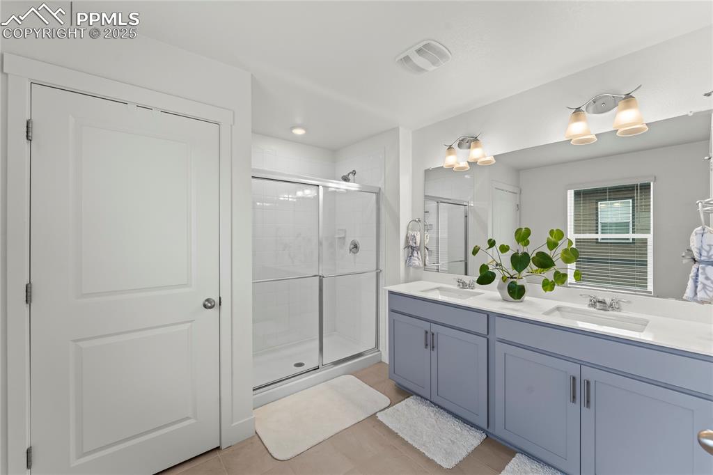 Image 30 of 39: Full bathroom with a shower stall, double vanity, and light tile patterned 