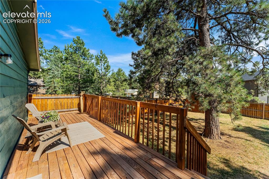 Image 12 of 32: Wood deck with railing overlooking a fenced yard