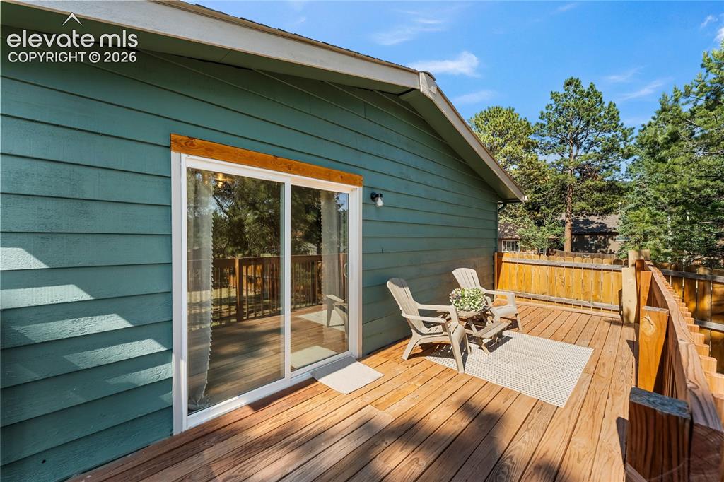Image 13 of 32: Spacious wood deck featuring a sliding glass door, rich wood railing, and a