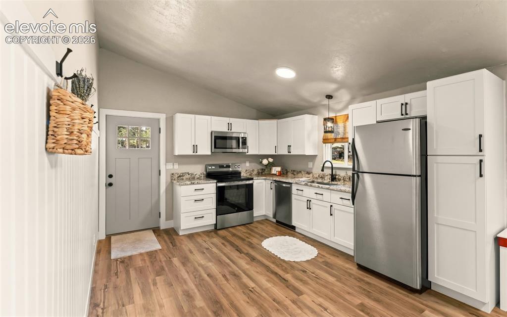 Image 17 of 32: Modern kitchen featuring wood-finish flooring, white shaker cabinetry with