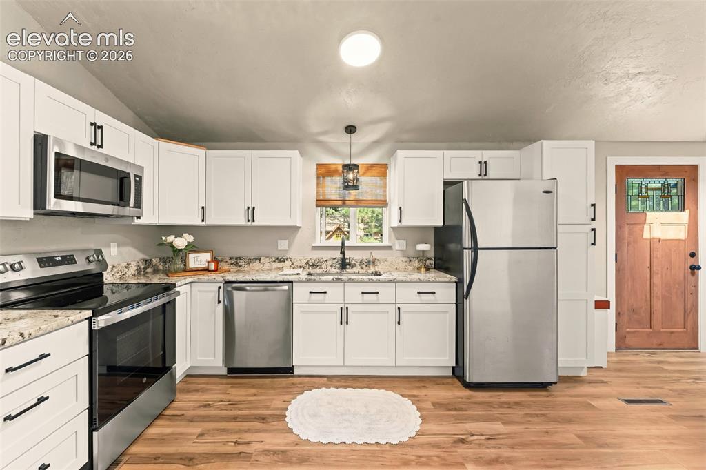 Image 18 of 32: Kitchen featuring white shaker-style cabinetry with matte black hardware, s
