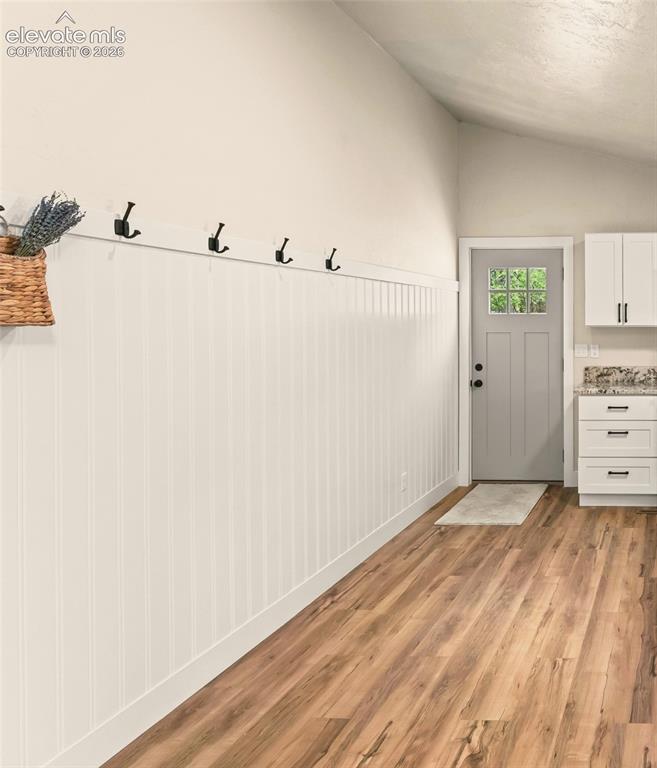 Image 19 of 32: Entryway featuring vertical beadboard paneling, integrated coat hooks, and