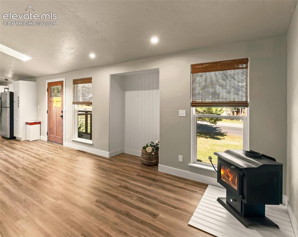 Image 21 of 32: Wood-finish flooring throughout, featuring a freestanding wood-burning stov