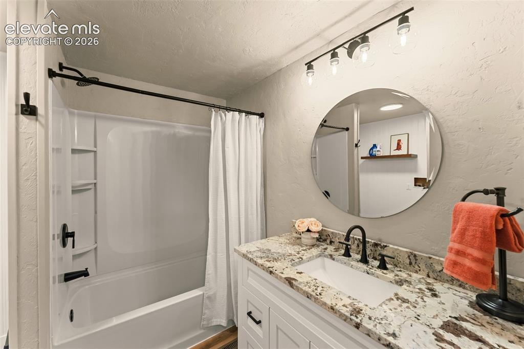 Image 23 of 32: Bathroom featuring a white vanity with a rectangular undermount sink, grani