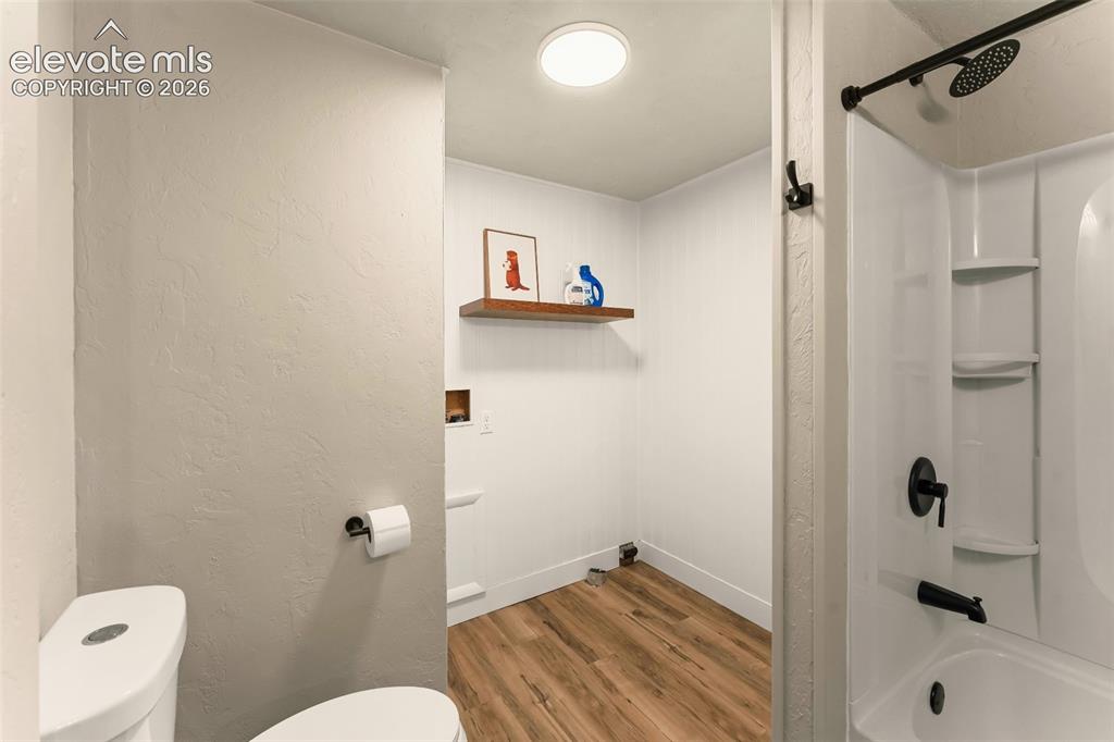 Image 24 of 32: Compact bathroom featuring a white toilet, black plumbing fixtures, a white