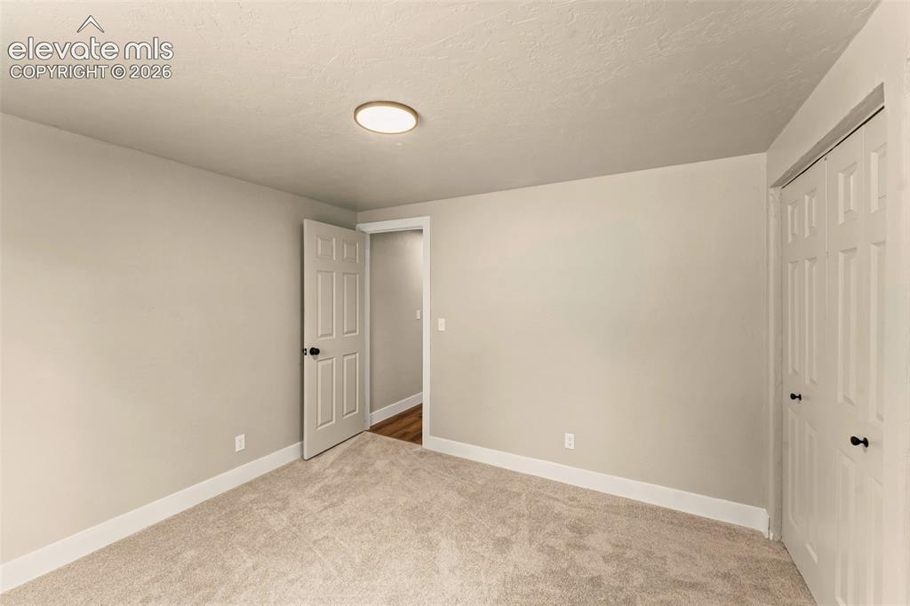 Image 27 of 32: Neutral-toned room with plush carpet flooring, white baseboards, and a flus