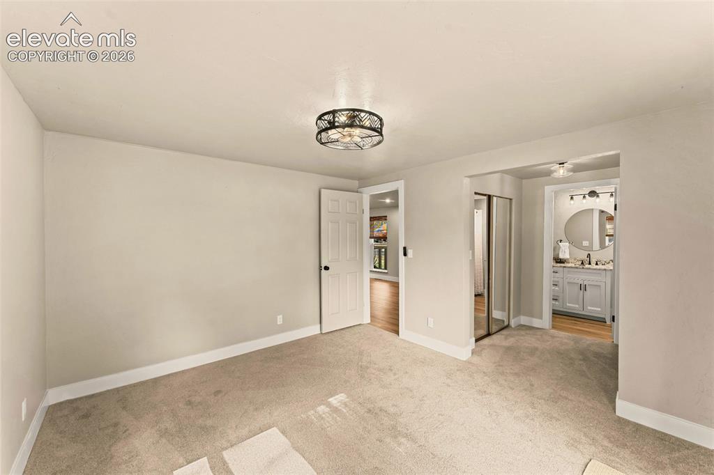 Image 28 of 32: Carpeted room with a ceiling-mounted light fixture, white baseboards, and n