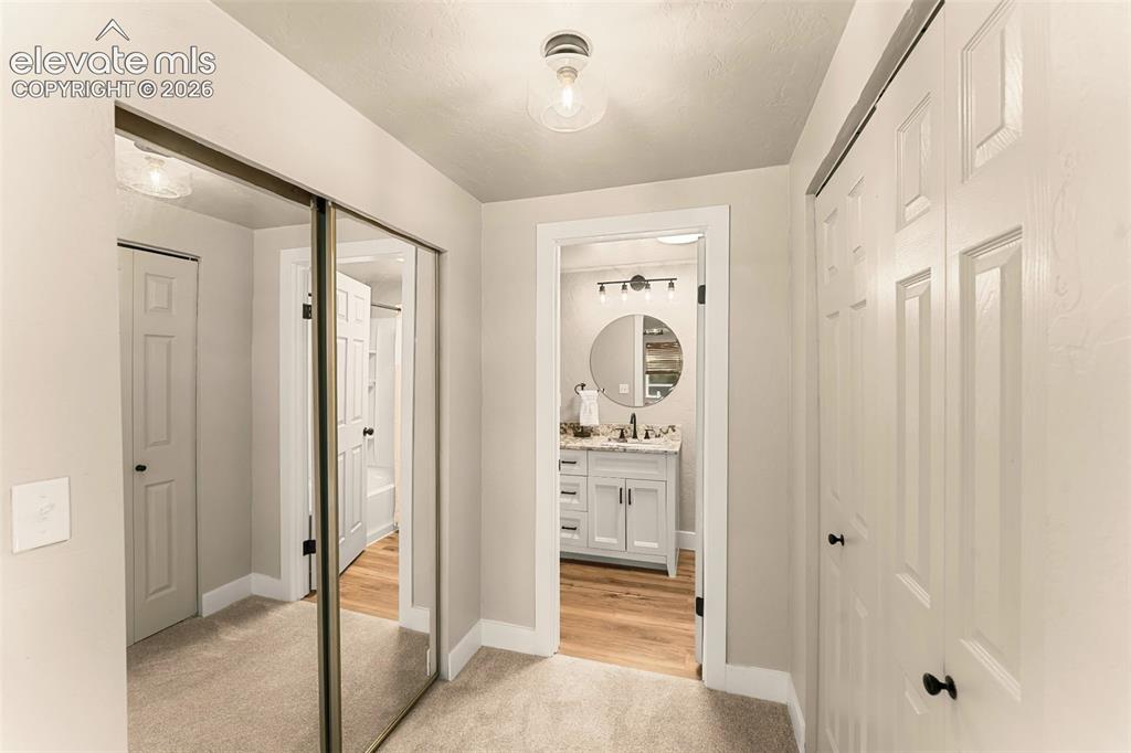 Image 29 of 32: Hallway featuring mirrored closet doors, a paneled bifold closet door, and