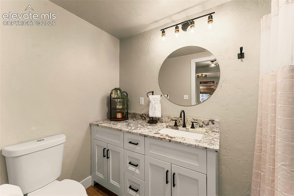 Image 30 of 32: Bathroom vanity featuring a granite countertop, undermount sink, and matte